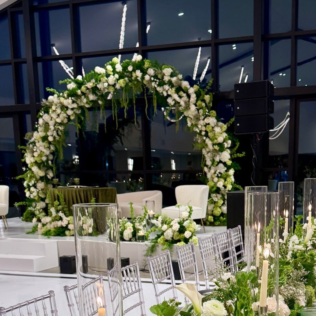 Elegant wedding reception setup with floral arch and table decorations.